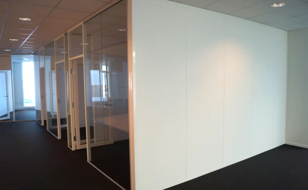 Lys, tett systemvegg kombinert med glassfelt i et kontorlokale.